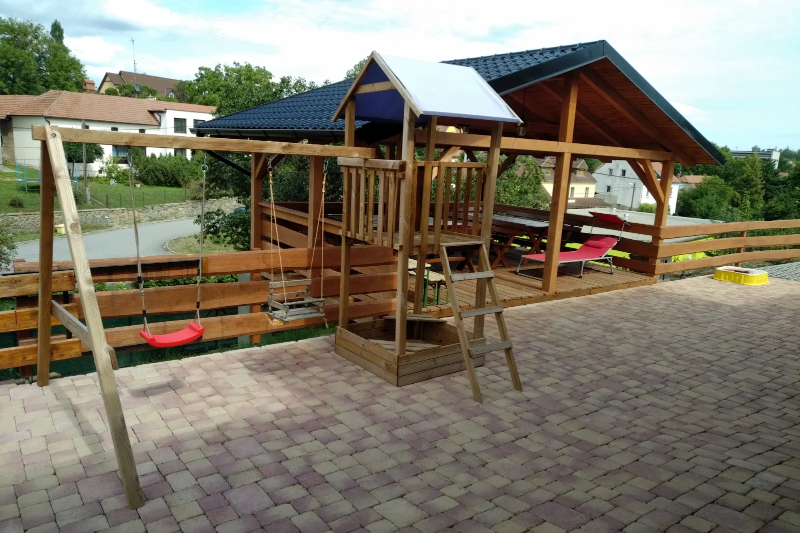 Zahrada s dětskými houpačkami a krytou pergolou
